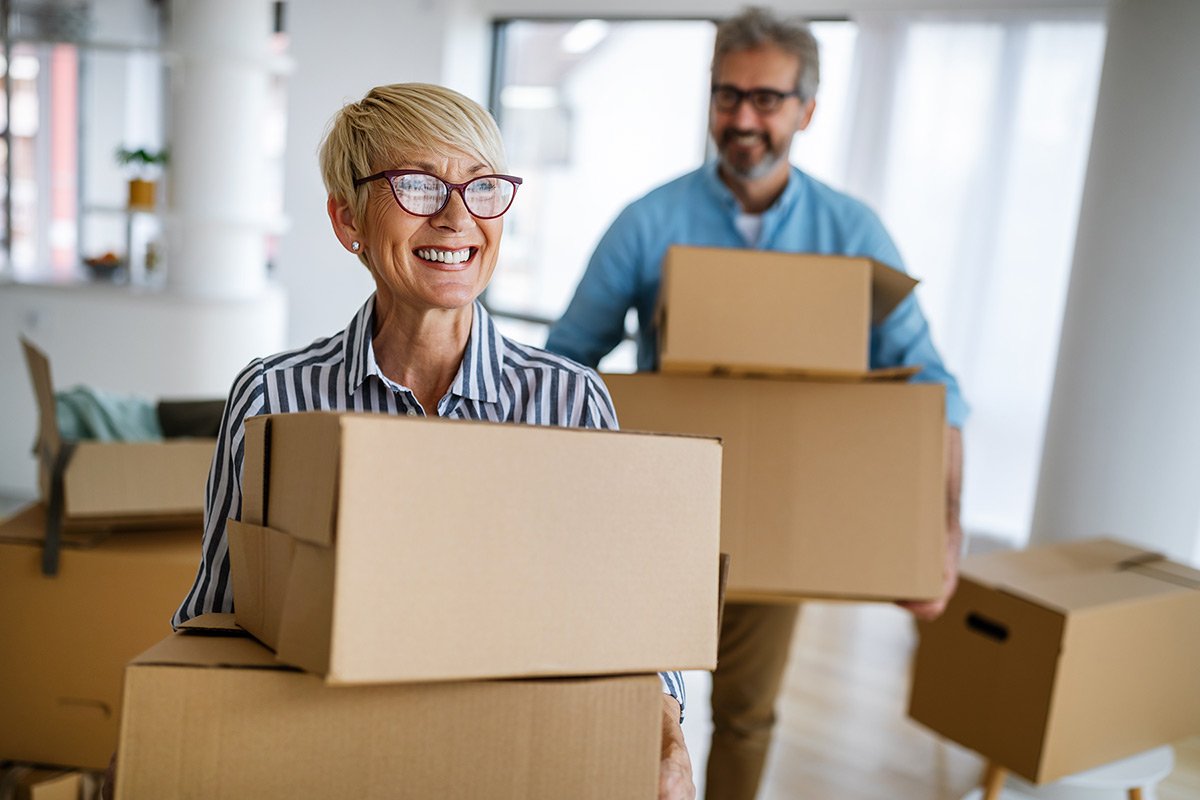 Smiling mature woman carrying boxes into her new house.