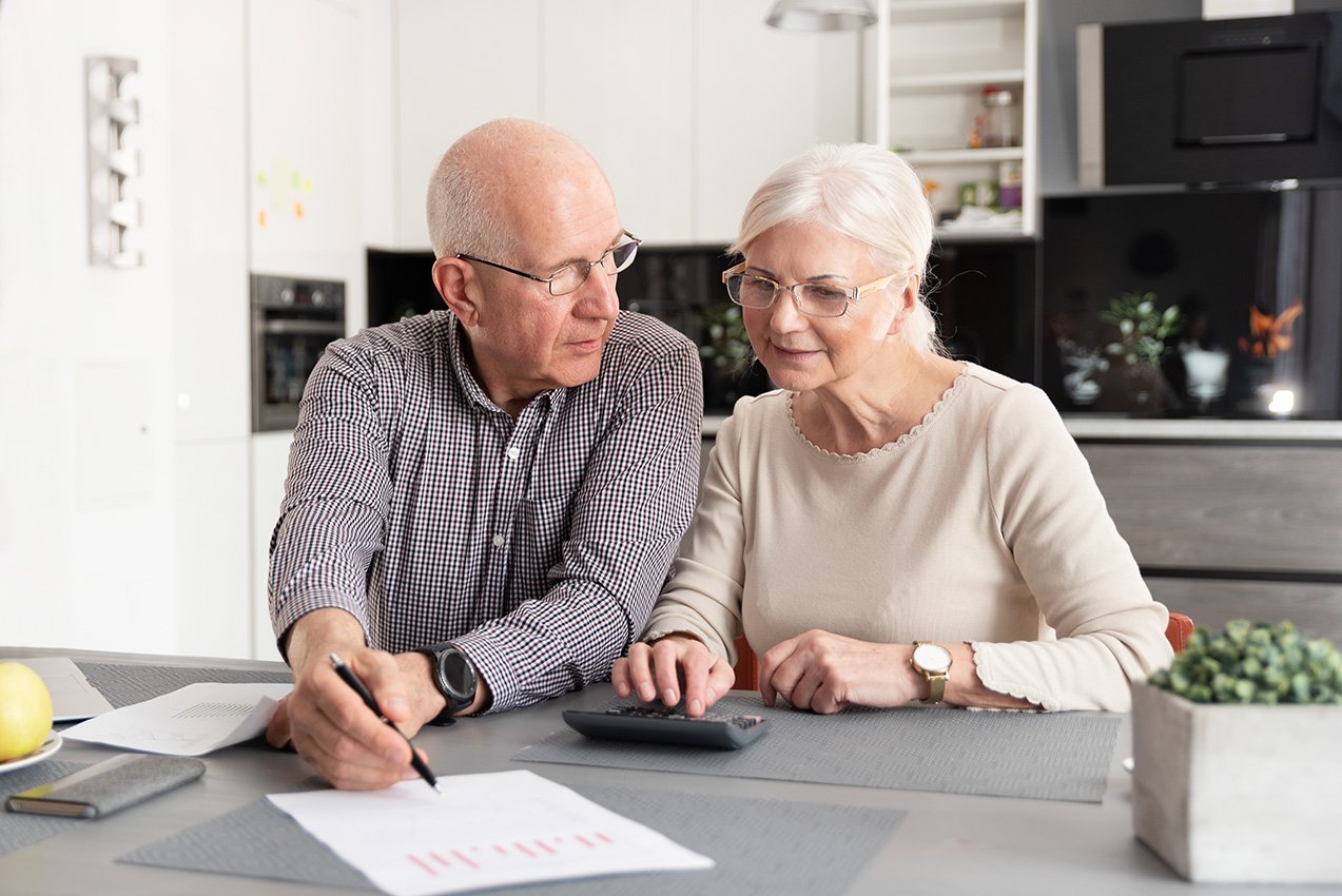 Mature Couple reviewing their finances at their kitchen table.