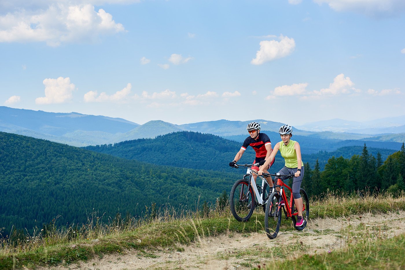 Middle-aged couple mountain-biking in the mountains.