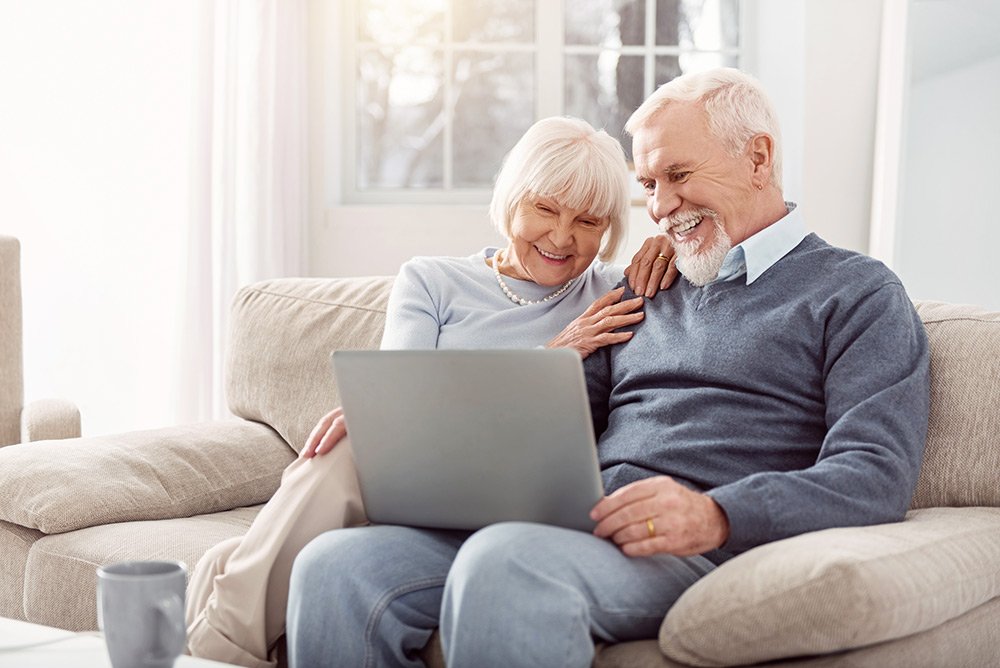 Happy senior couple sitting on the couch with a laptop.