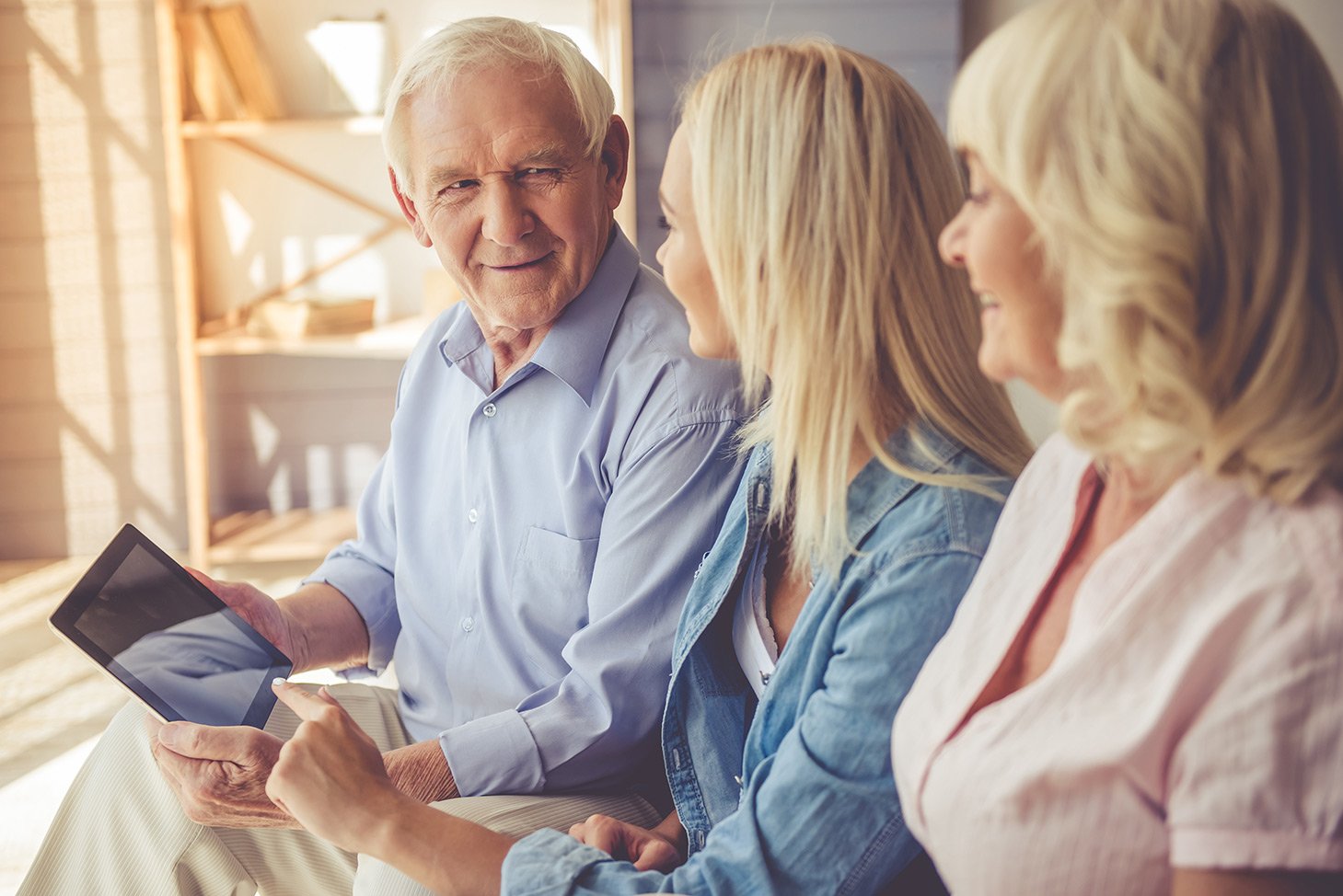 Senior couple holding an ipad talking to their daughter about transferring wealth.