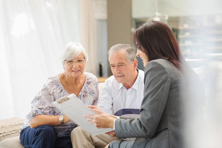 Senior couple talking with financial planner in their home.