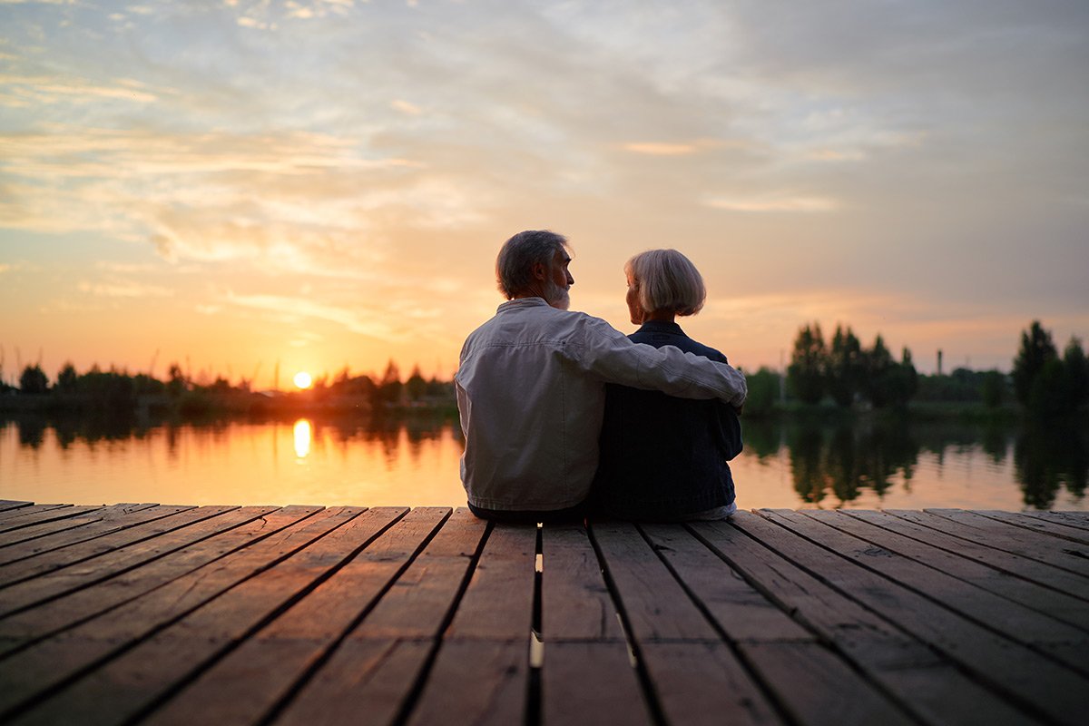 Couple sitting on a dock at sunset.