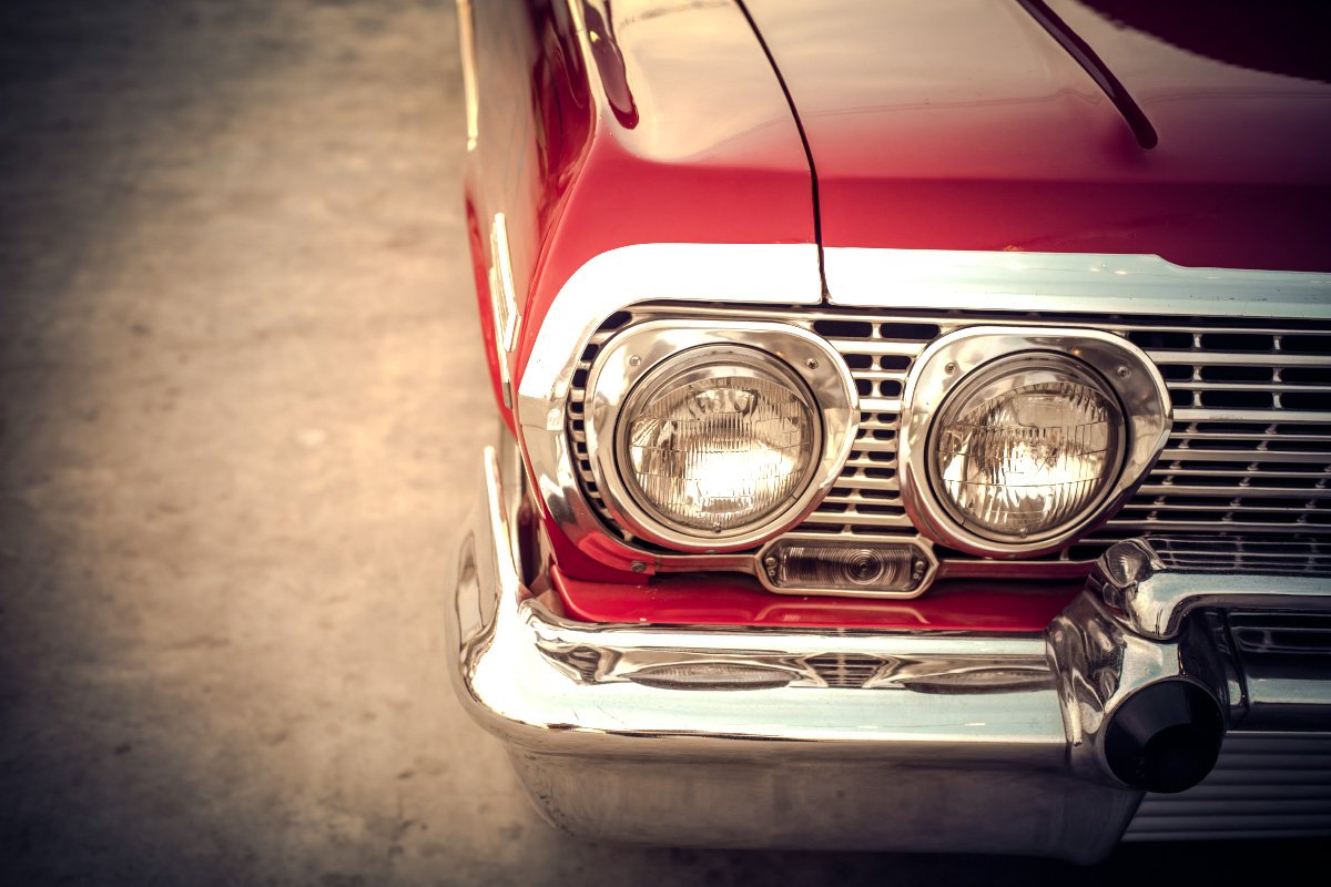 Close-up of red antique car's headlight.