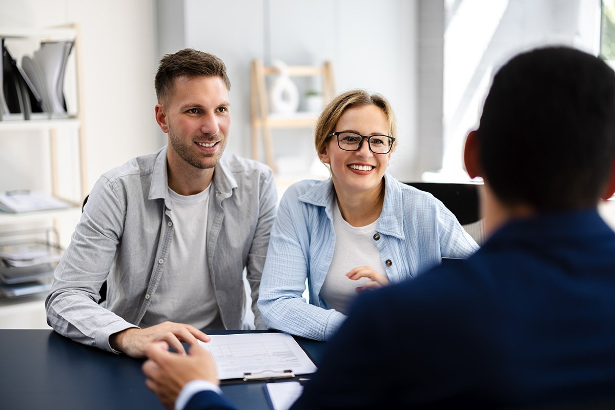 Happy, young couple talking with their financial planner.