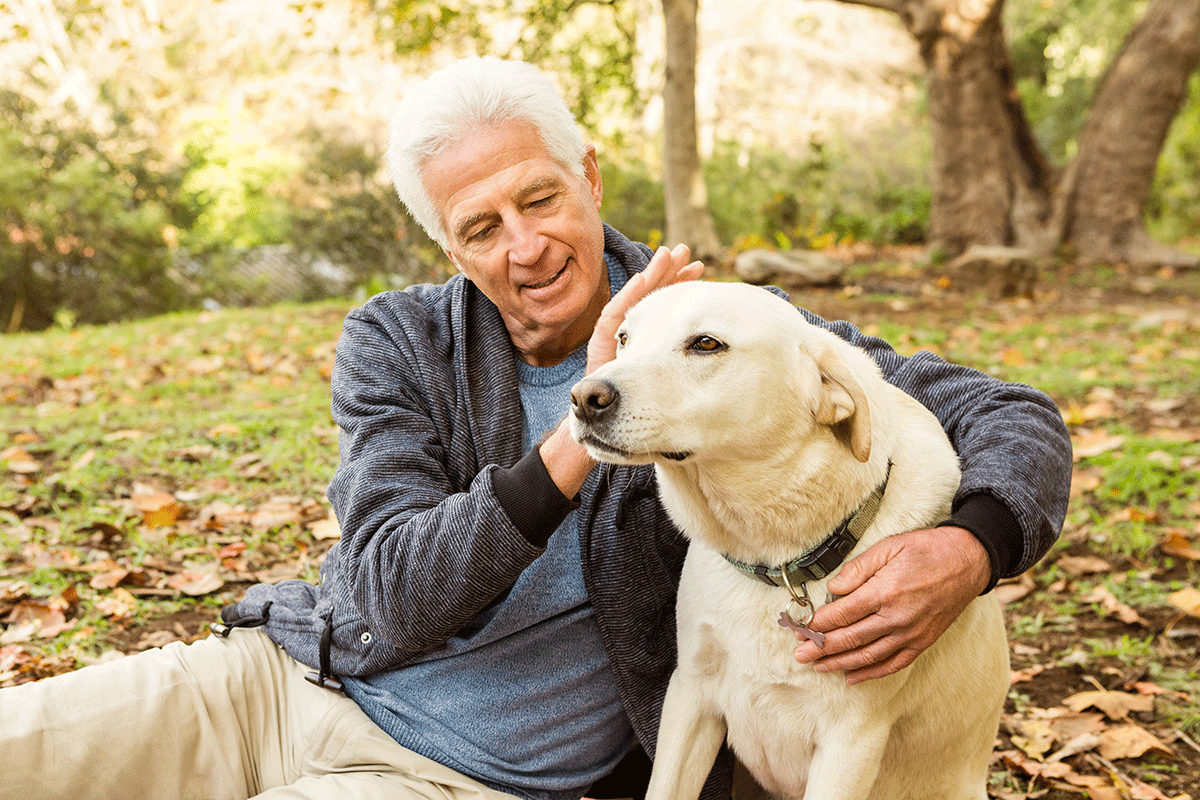 Retired man with his dog sitting on the ground.