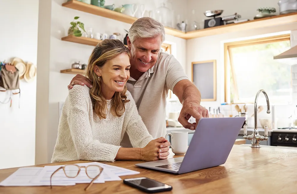 Mature couple looking at their laptop to learning about the services offered by Aspire Wealth Group.