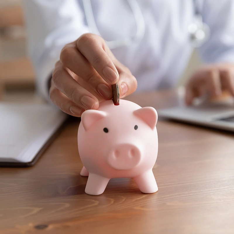 Individual adding coin to piggy bank.