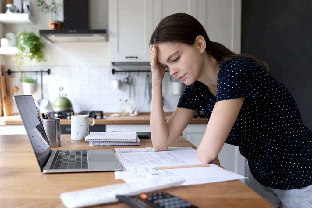 Young woman reviewing her finances, with a disappointed look.