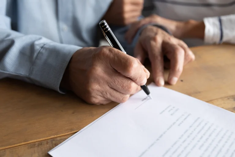 Closeup of Individual signing his name on a document.