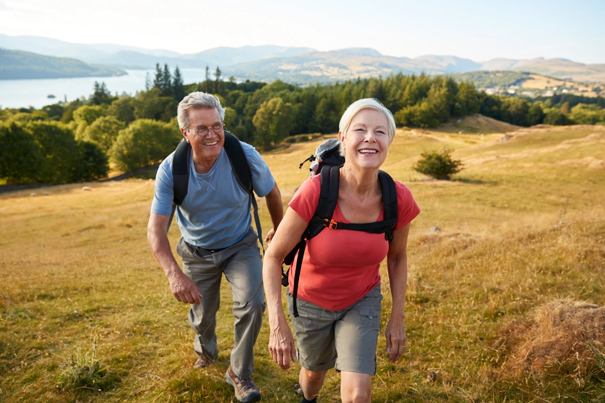 Retired husband and wife hiking in the hills.