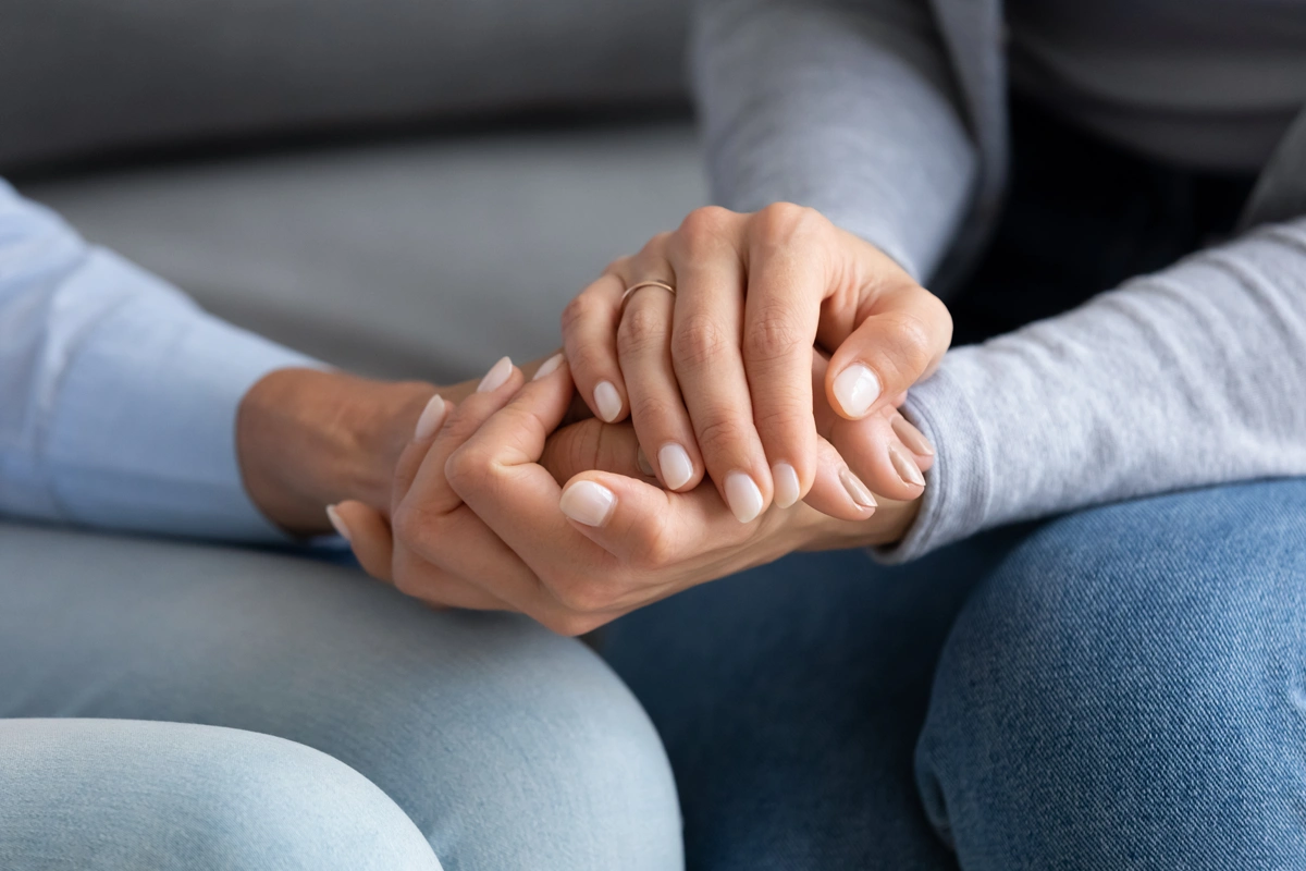 Closeup of a pair of young hands holding the hand of an elderly person.