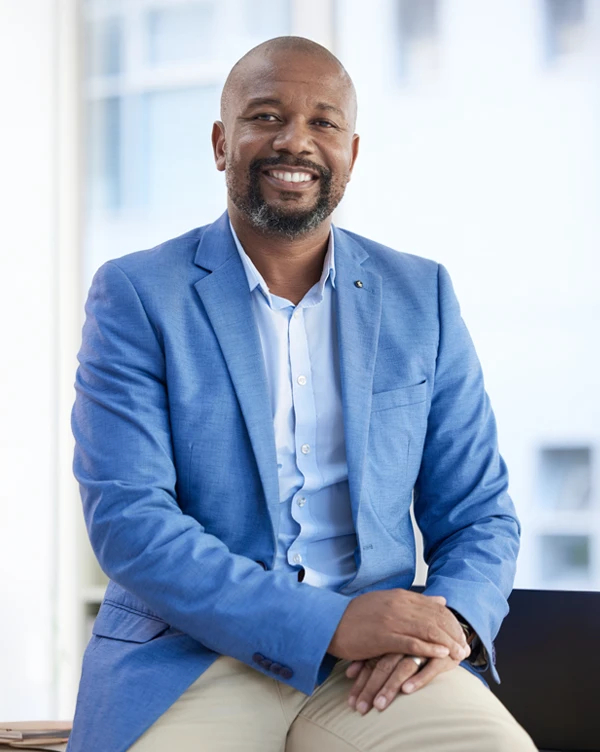 An African American business owner sitting at his desk posing for a photo.