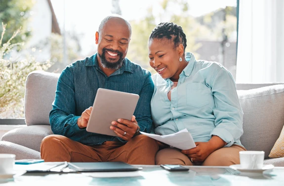 Mature African American couple looking at finance statements on tablet.