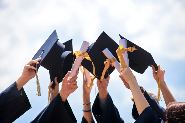 Graduates raising their graduation caps into the air.