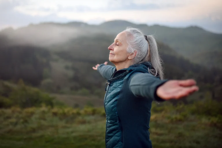 Woman on a hilltop at peace with arms held out.