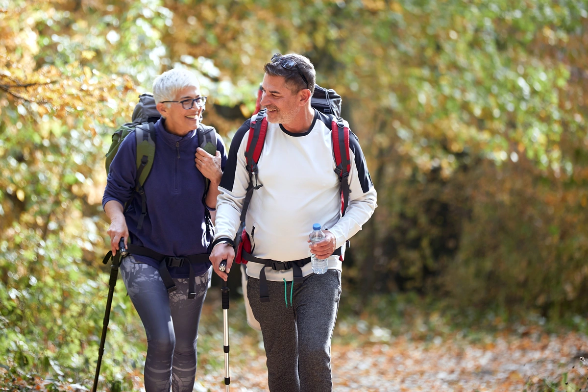 Retired couple hiking on a trail in the fall.