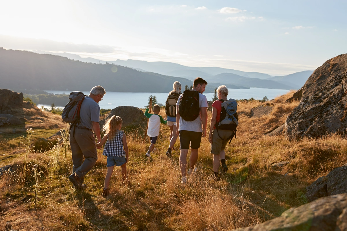 Multi-generational family walking on trail overlooking a lake.