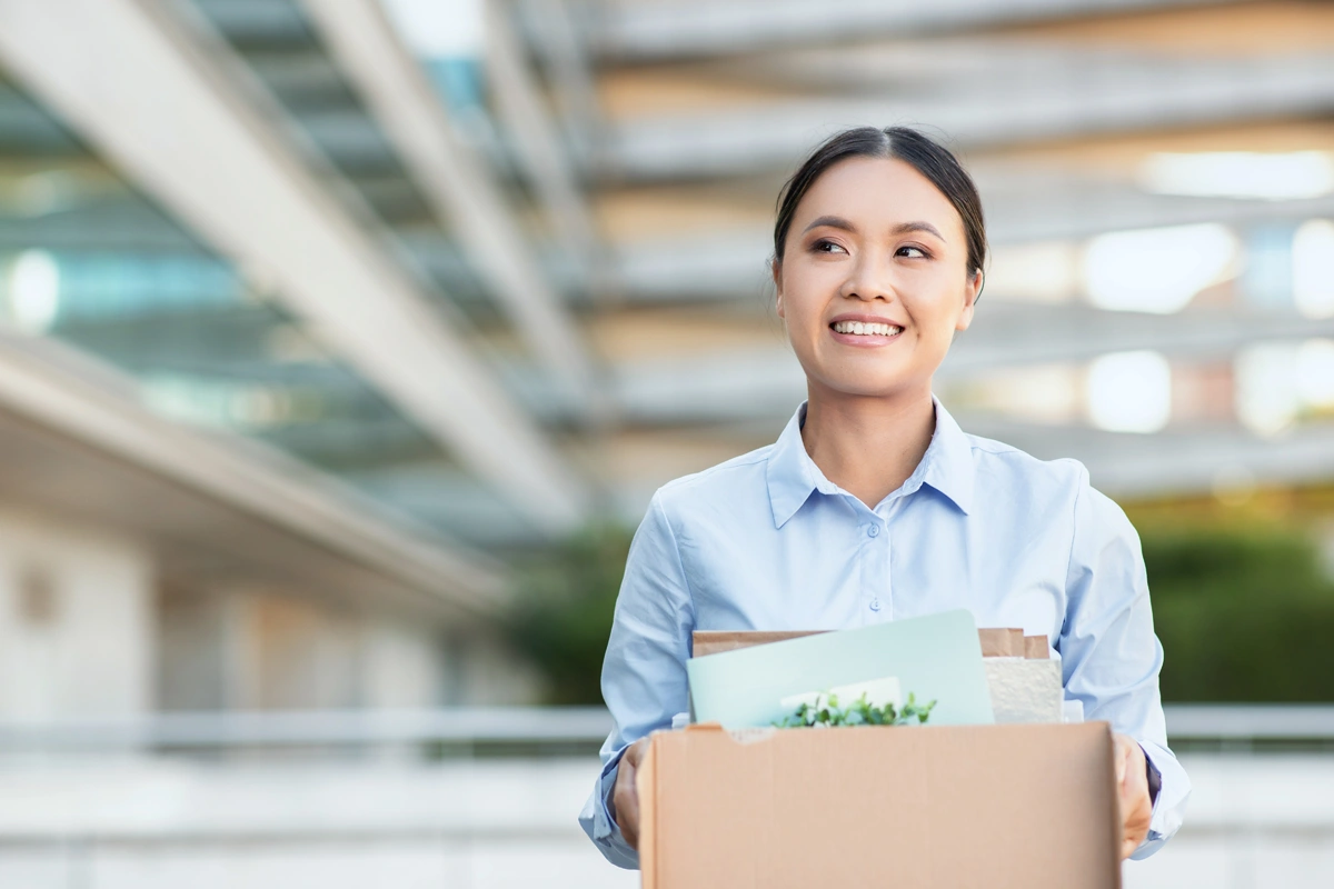 Young businesswoman holding box of belongings as she changes jobs.
