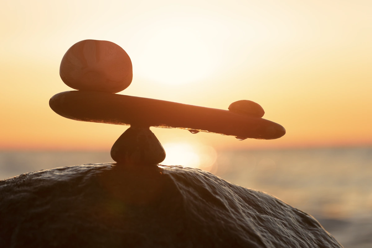 Silhouetted stones balanced on a rock at a beach.
