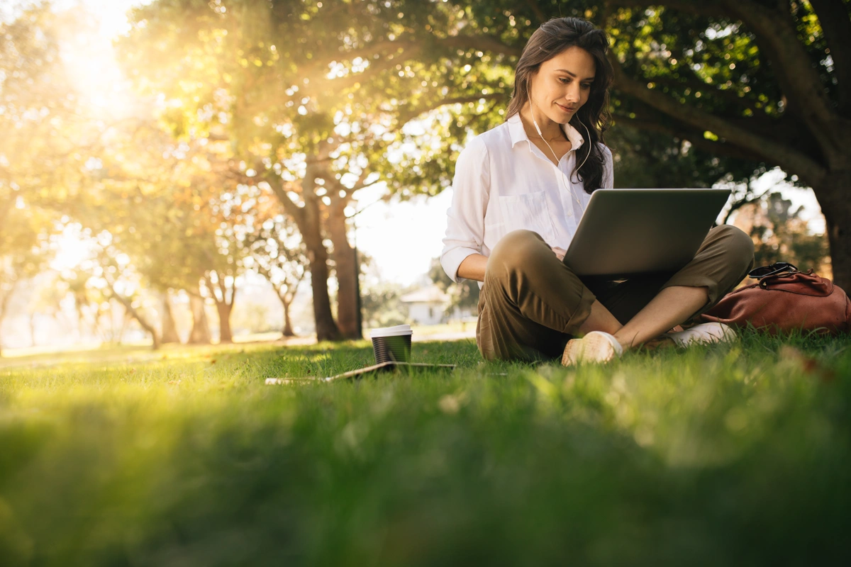 Young woman sitting outdoors with laptop reviewing budget.