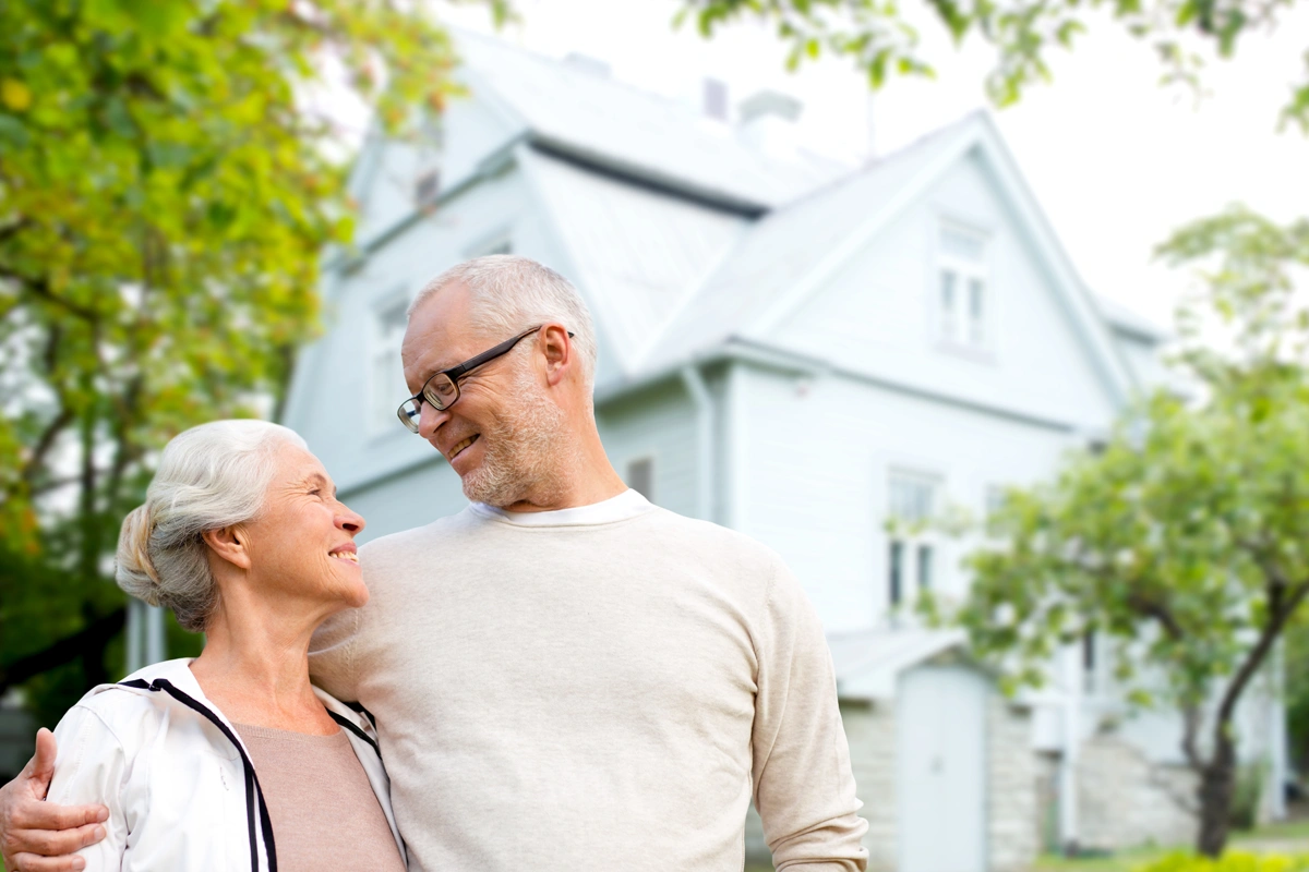 Senior couple standing outside their home.