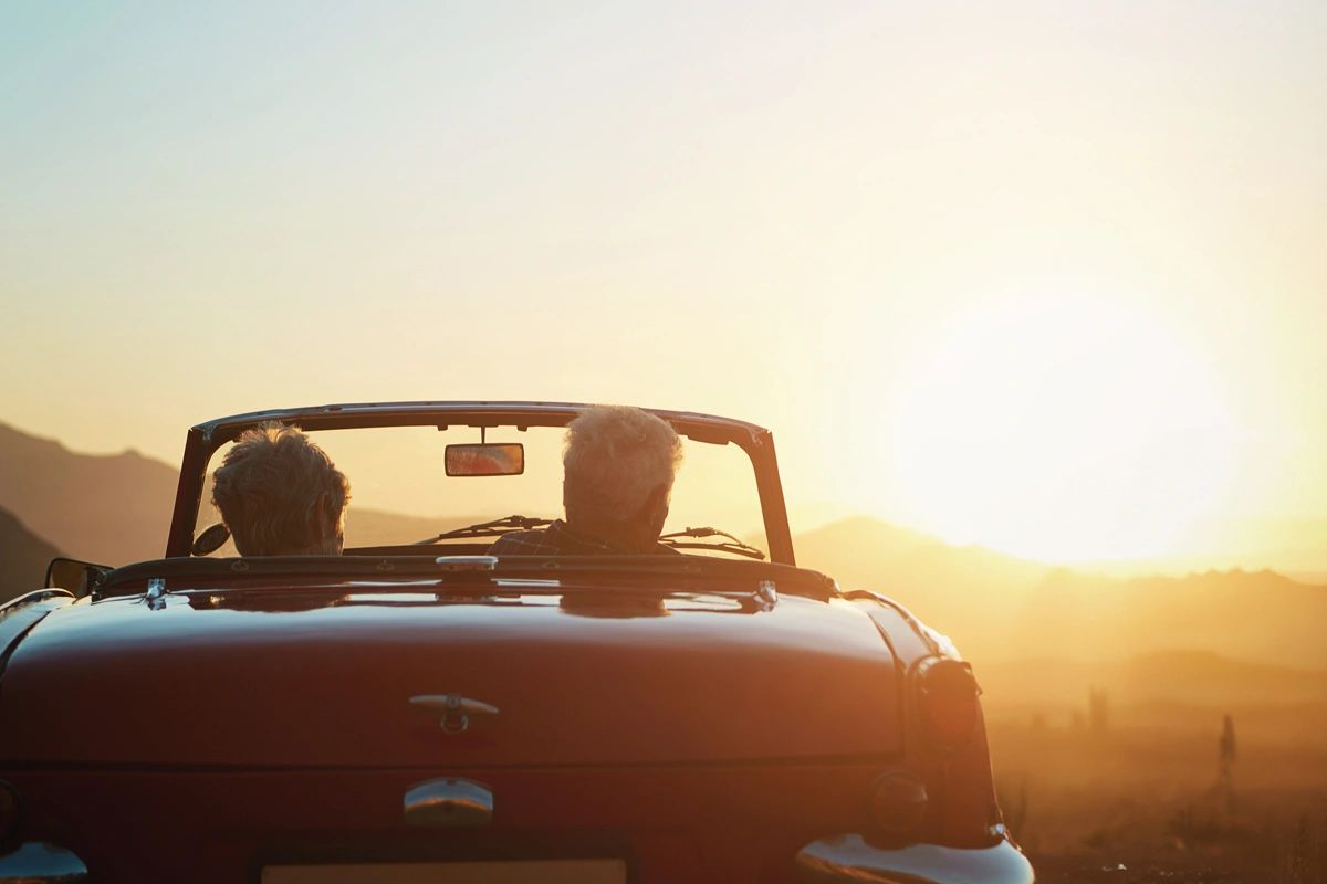 Couple sitting in convertible watching the sunrise.