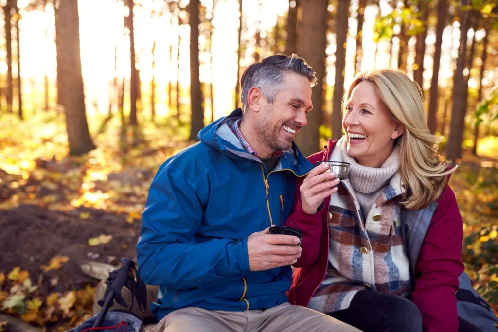 Retired couple sitting, taking a break from hiking in the woods.